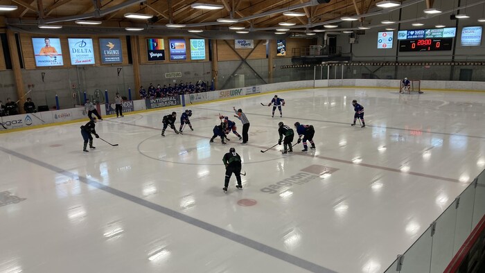 Des joueurs de hockey sur une glace dans un aréna.