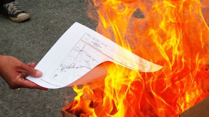 Une personne tient une feuille qui prend feu.