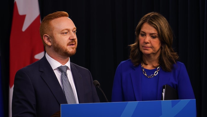Mickey Amery parle devant un lutrin le 29 avril 2025. Danielle Smith se trouve à ses côtés.