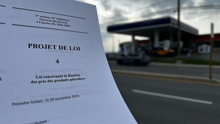 Un document à l'avant-plan, une station-service derrière.