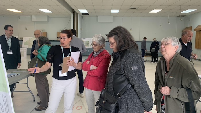 Plusieurs personnes écoutent les explications données par une femme. 