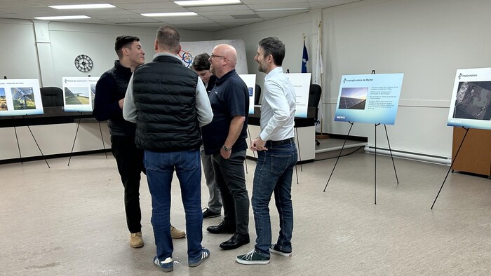 Des gens discutent dans une salle avec des affiches.