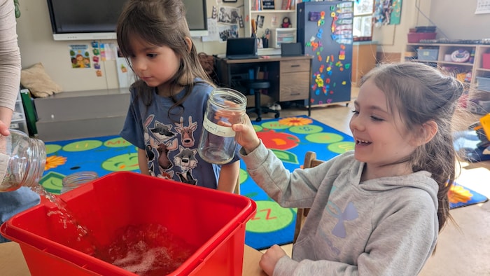 Une petite fille rit, un pot à la main, pendant qu'un produit nettoyant est vidé dans un bac.