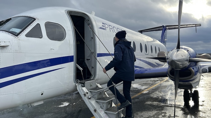 Un homme monte dans un avion, sur le tarmac.