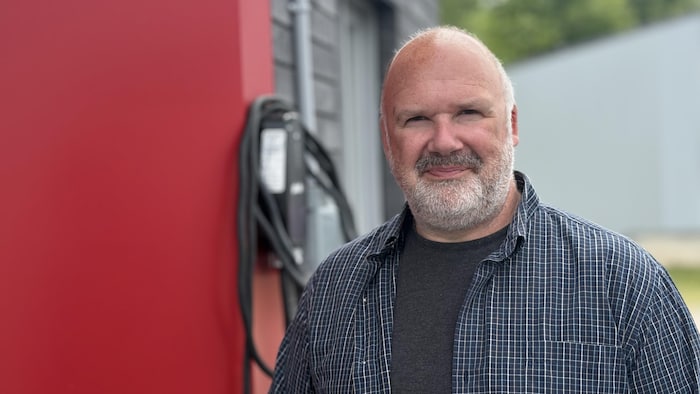 Un homme devant une borne de recharge pour véhicule.
