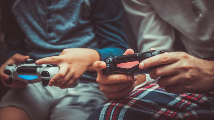 Un adulte et un enfant jouent ensemble à un jeu vidéo. 