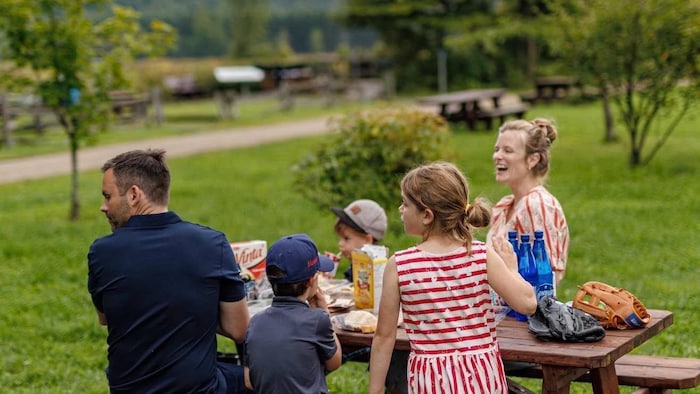 Paul St-Pierre Plamondon assis à une table de pique-nique avec sa conjointe et ses trois enfants.