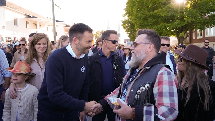 Paul St-Pierre Plamondon serre la main d'un homme, souriant, dans une foule.