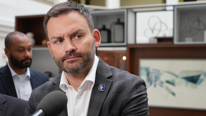 Paul St-Pierre Plamondon, les bras croisés, écoute les journalistes devant des microphones.
