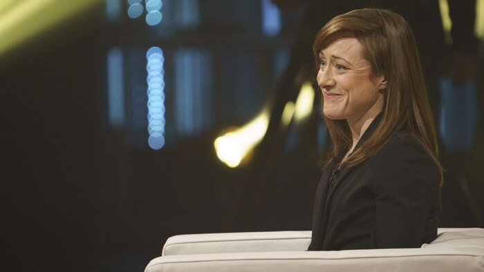 Mme Vachon est assise sur un fauteuil.