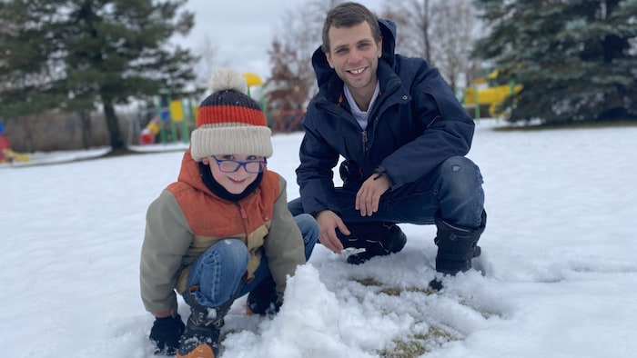 Un père et son fils jouent dans la neige.