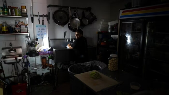 Employees at Las Palmas Café work with the power of an electrical generator during an island-wide blackout in San Juan, Puerto Rico on April 7, 2022. (Carlos Giusti/The Associated Press)