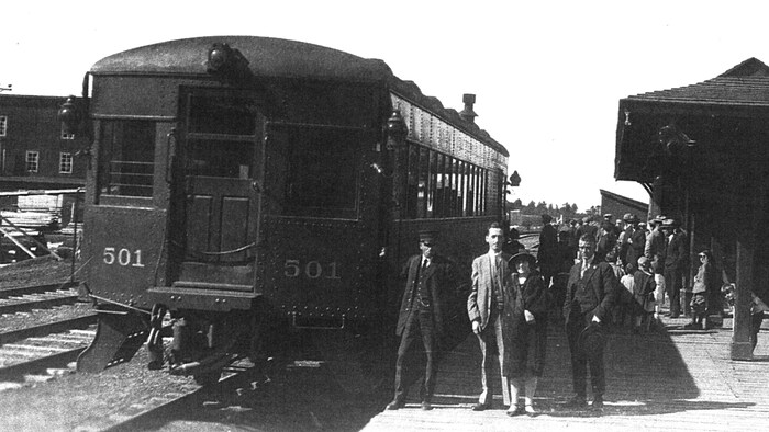 Des femmes et des hommes bien habillés à côté d'un train.