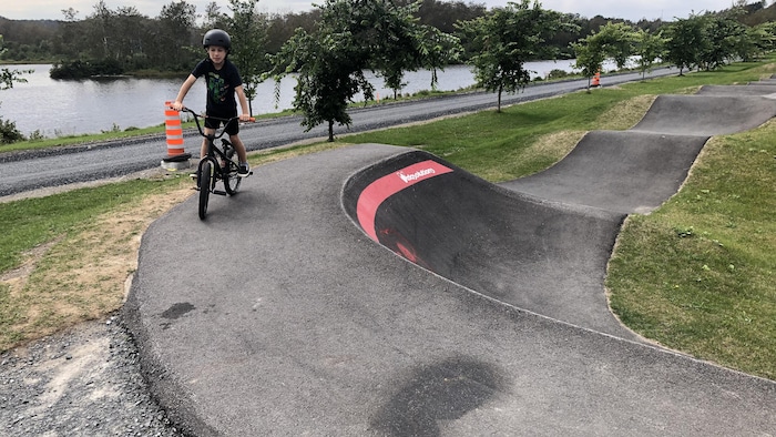 Un garçon sur un vélo qui parcourt la piste asphaltée sur le bord de la rivière Matane.