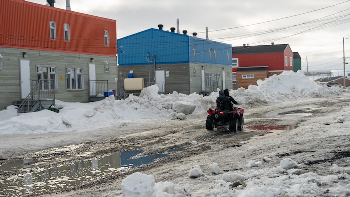 Une rue enneigée sur laquelle circule un VTT à quatre roues.