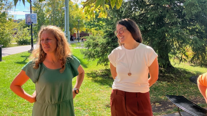 Deux femmes se tiennent côte à côte à l'extérieur.