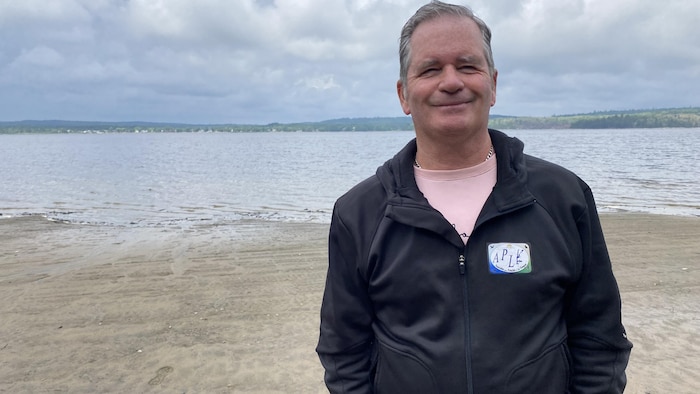 Un homme pose devant un lac.