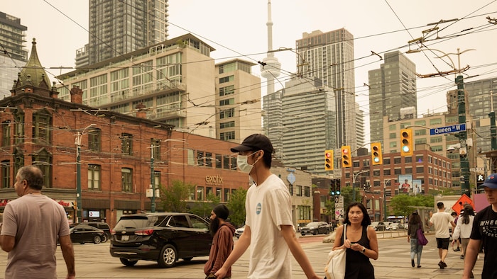 Des passants à l'intersection Queen et Spadina.