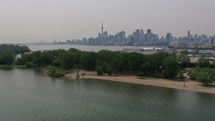 Photos aériennes de l'horizon enfumé de Toronto avec en avant-plan, la plage de l'île Ward.