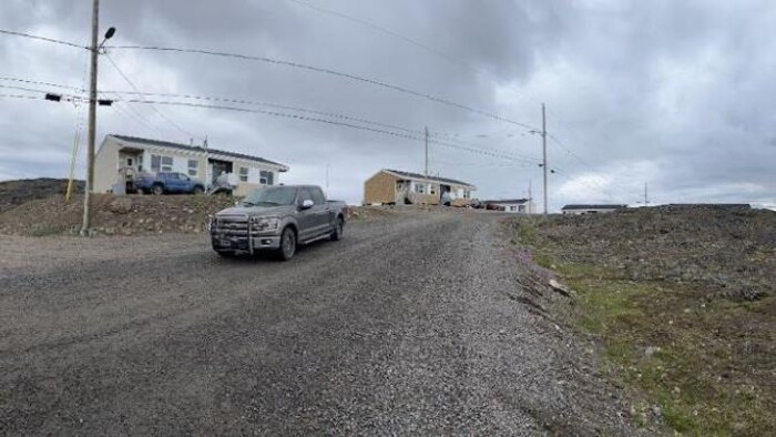 Un camion roule sur une route de gravier qui traverse un petit hameau en région éloignée.