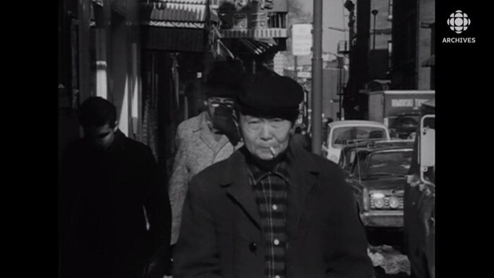 Un homme âgé (probablement d'origine chinoise) avec une cigarette dans la bouche qui marche dans le quartier chinois de Montréal.
