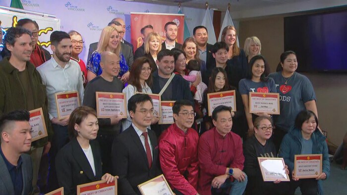 Un groupe de personnes tenant des certificats dans leurs mains sourient à la caméra.