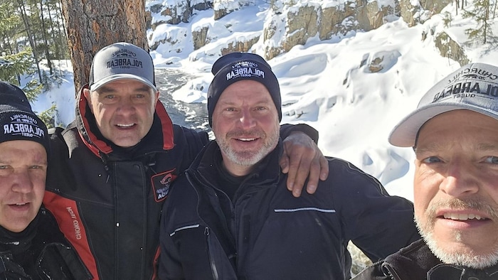 Portrait des quatre hommes dans un paysage enneigé.