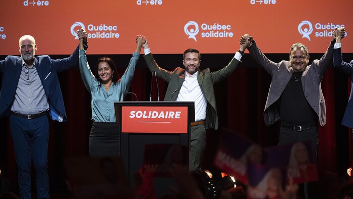 Cuatro personas levantan los brazos en señal de victoria.
