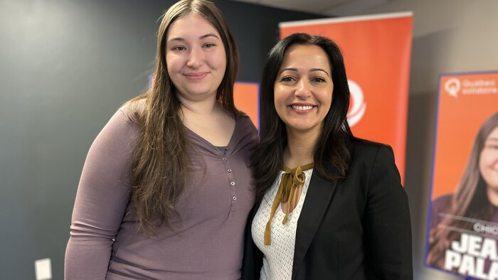 Deux femmes posent devant des affiches de Québec solidaire.