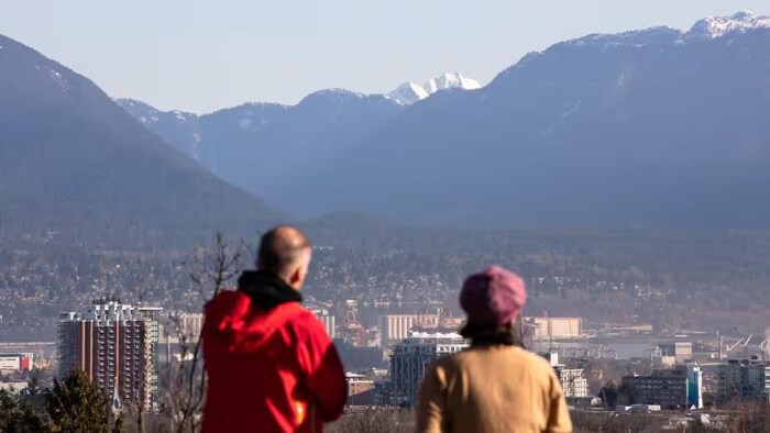 Deux personnes regardent des montagnes au loin.