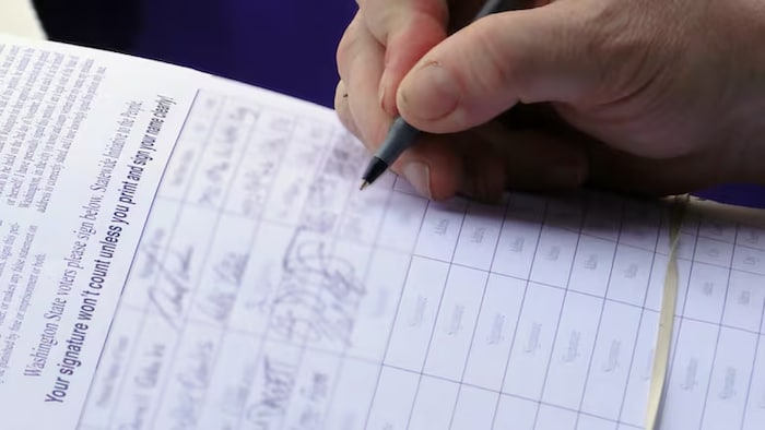 Une personne tenant un stylo devant un papier.