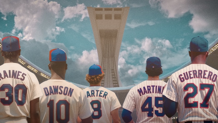 Baseball players are seen from behind in front of the Olympic Stadium flagpole. 