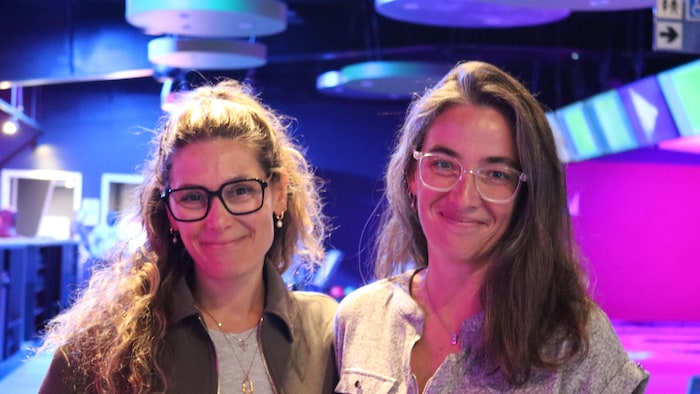 2 femmes qui sourient dans un salon de quilles.