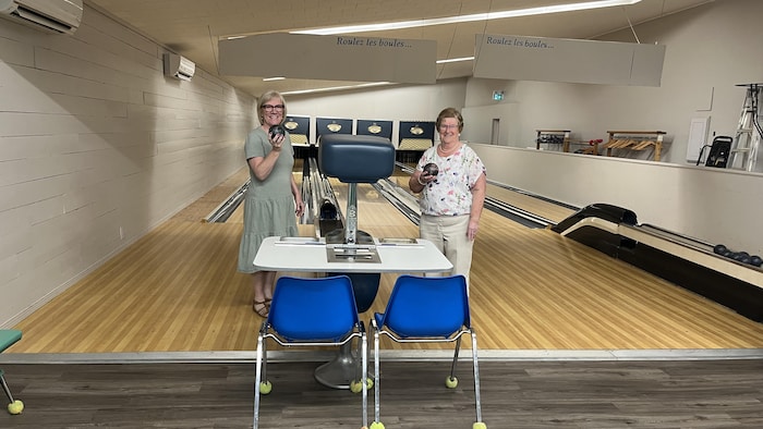 Robéa Cormier et Réjeanne Doiron tiennent des boules dans la salle de quilles.