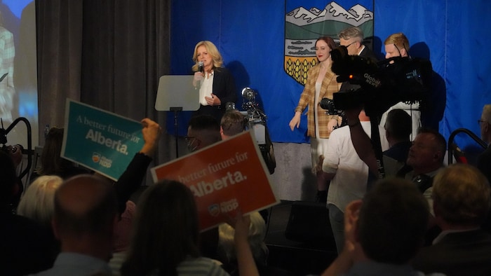 Rachel Notley sur scène, sa famille à côté, au premier plan la foule de partisans avec des pancartes, au quartier général du NPD, à Edmonton, en Alberta, le 29 mai 2023.