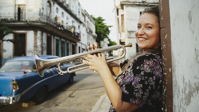 Rachel Therrien tient sa trompette en souriant dans une rue de Cuba.