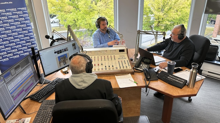 Trois hommes dans un studio de radio prennent la parole.