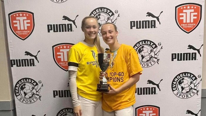 Les deux joueuses sourient avec un trophée dans les mains.