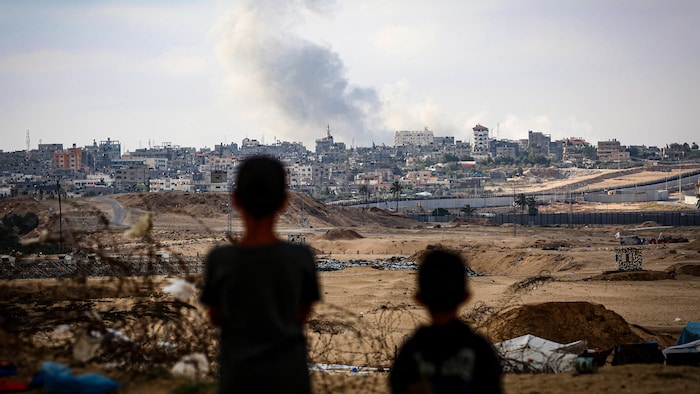 Des garçons regardent la fumée qui se dégage des frappes israéliennes à l'est de Rafah, dans le sud de la bande de Gaza, le 13 mai 2024.