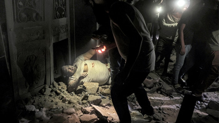 فلسطينيون يستخدمون الأضواء المنبعثة من هواتفهم المحمولة لإنقاذ جريح من تحت أنقاض مبنى استهدفه القصف الإسرائيلي في مدينة رفح.
