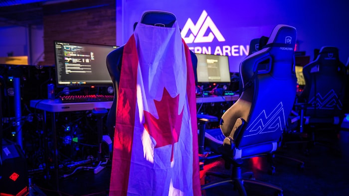 Une photo montrant un drapeau canadien suspendu à une chaise de bureau devant un ordinateur.