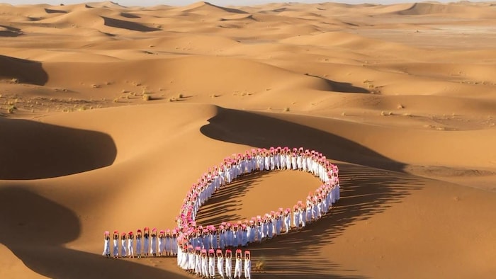 Des femmes forment un ruban rose dans le désert.