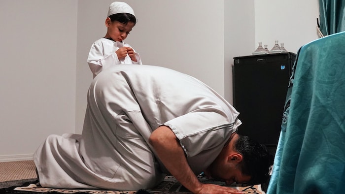 Un père et son fils prient dans une pièce.