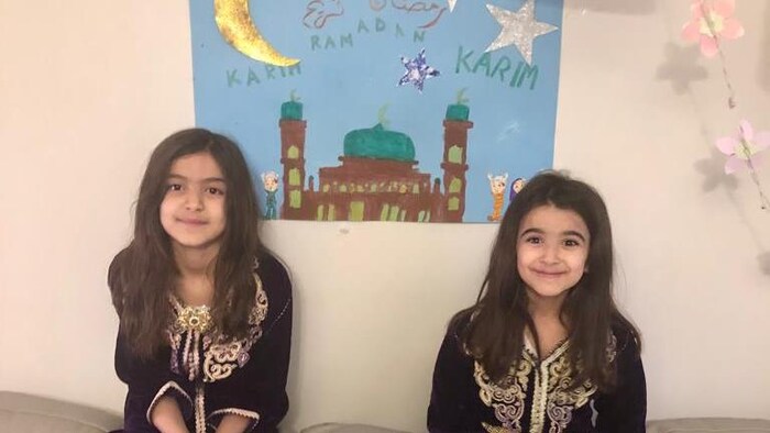 Deux filles devant une affiche qui célèbre le ramadan.