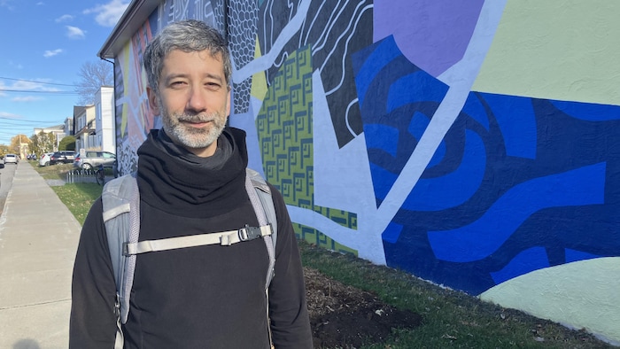 Portrait de Raphaël Arsenault devant la murale de la Coopérative Paradis dans le quartier Saint-Robert.