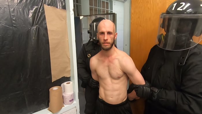 Capture d'écran d'une vidéo montrant le suspect torse nu entouré d'agents de force de l'ordre. 