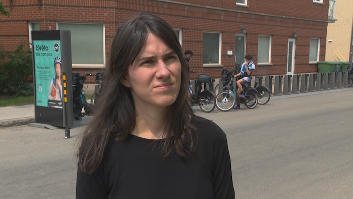 Elle est en entrevue devant une station àVélo.
