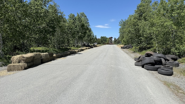Une côte bordée d'arbres avec des balles de foin d'un côté et des vieux pneus de l'autre.