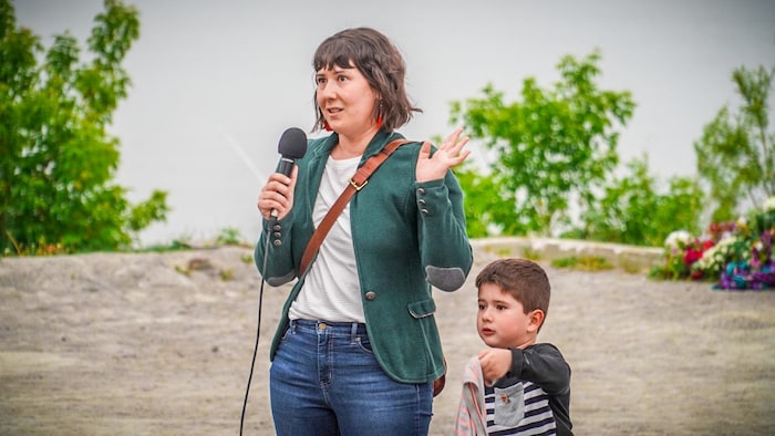 Chloé Dugas avec un micro sur le bord du fleuve et son fils qui tient un chandail près du fleuve Saint-Laurent.