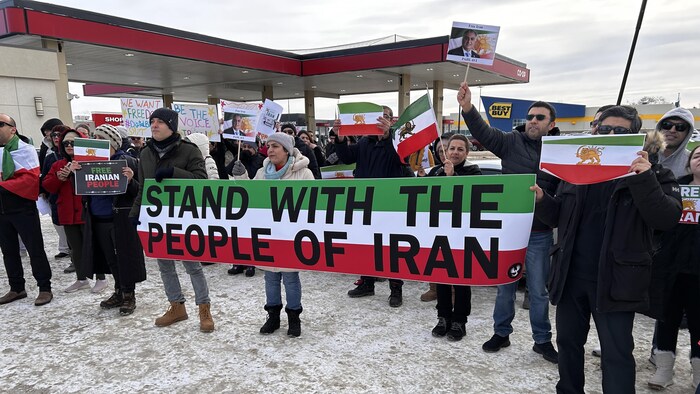 Des personnes debout tiennent le drapeau iranien, le 11 janvier 2026 à Saskatoon.